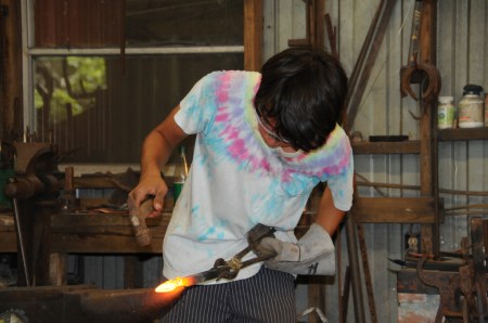 Jakob, following Buddy's instructions, forges a sliding bolt piece